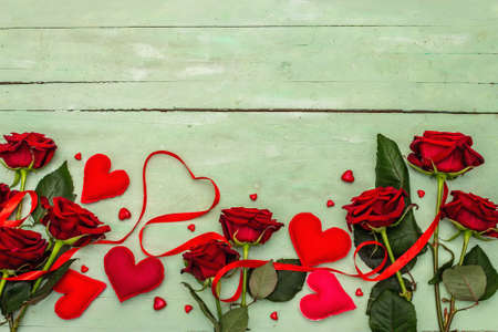 Valentines Day background with assorted hearts, fresh burgundy roses and red festive ribbon. Old...