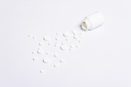 White pharmaceutical medicine pills, tablets, and capsules for the treatment of disease isolated on white background. Bottle of pills, copy space for textの写真素材