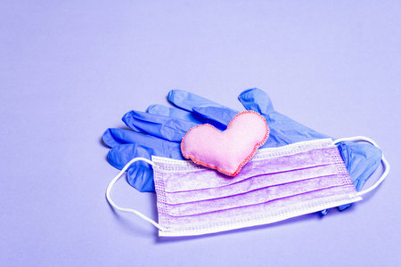 Lilac heart with medical protection masks and gloves on light purple background, copy space. Concept...