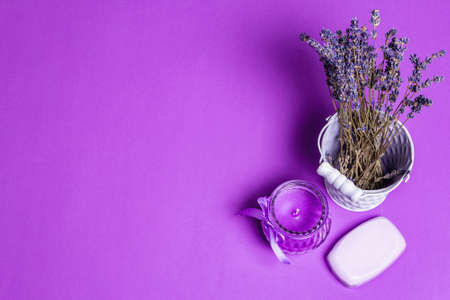 Monochromatic lavender spa concept. Fragrant flowers in the bucket, natural soap, and a purple candle. Matte lilac background, place for textの写真素材