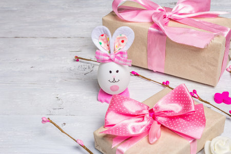 Handmade traditional Easter symbols concept. Cute rabbit from the egg, gift box, festive decor in...
