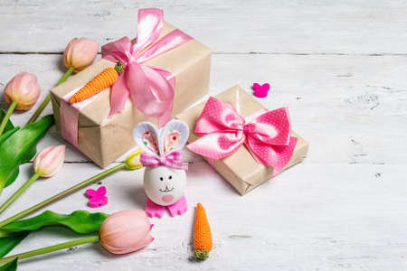 Handmade traditional Easter symbols concept. Cute rabbit from the egg, gift box, festive decor in...