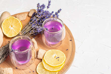Lemonade with lemons and lavender. A refreshing low alcoholic drink with fresh fruits and a dry bouquet. White putty background, copy spaceの写真素材