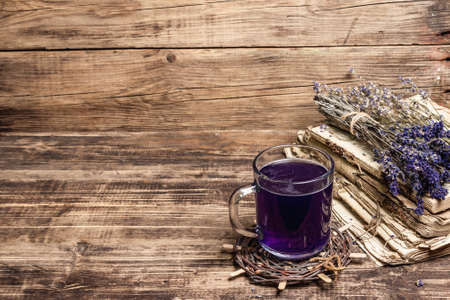 Lavender hot tea on vintage wooden table. Natural organic flower drink for morning good mood, old books, dry bouquet, copy spaceの写真素材