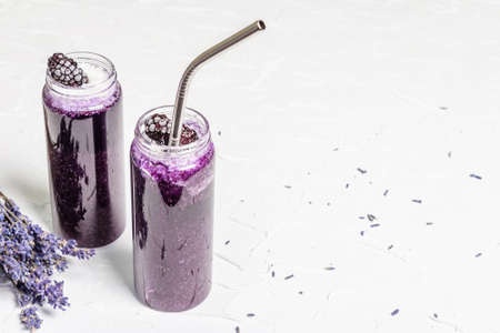 Lavender smoothie with coconut flakes and frozen blackberry. Dry flower bouquet, lilac napkin. White...