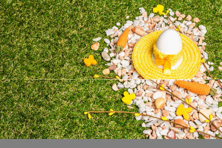 Unusual Easter background. Green grass, egg, scattered pebbles, festive decor. Handmade design, place for text, copy spaceの写真素材