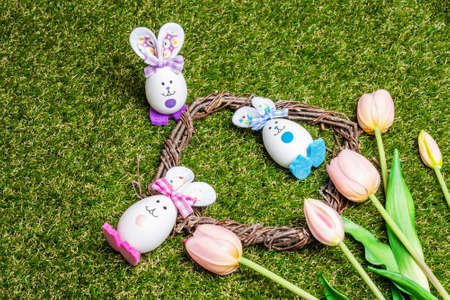 Traditional Easter symbols festive background. Handmade cute rabbits from eggs, wicker wreath and...