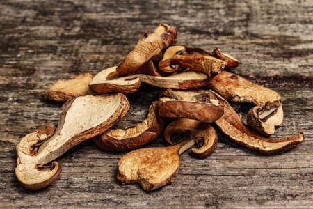 Forest dried edible mushrooms. Dehydrated slices, exquisite ingredient for cooking healthy food. Vintage wooden table, close upの写真素材