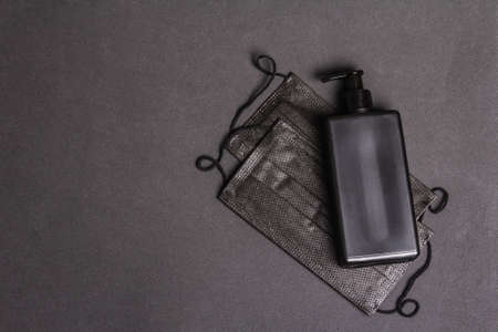 Surgical protective black masks and antiseptic isolated on dark background. Medical products for personal hygiene and the prevention of viral diseases.の写真素材