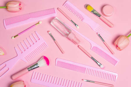 Makeup cosmetic set and hair combs on pink background. Professional decorative cosmetics, beauty...