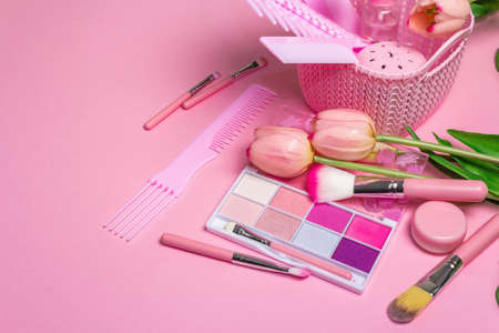 Makeup cosmetic set and hair combs on pink background. Professional decorative cosmetics, beauty...