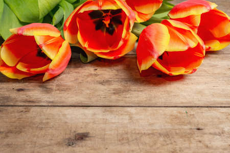 A festive bouquet of fresh tulips on a vintage wooden table. Spring flowers, Easter, or Mother's Day greeting card concept. Happy birthday or Women's Day holiday background. Flat lay, a place for textの写真素材