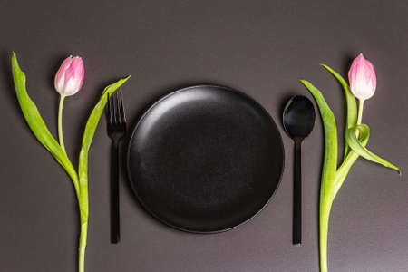 Festive creative black table setting with tulips on dark background. Valentine's Day, Wedding,...