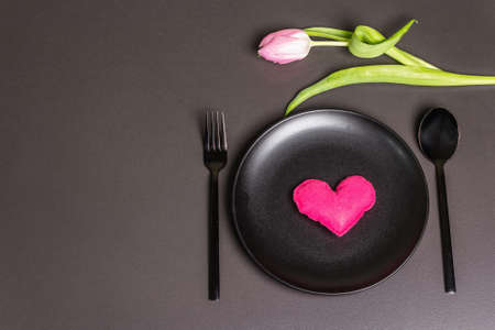 Festive creative black table setting with tulips and felt heart on dark background. Valentine's Day, Wedding, Birthday, Women's, and Mother's Day. Flat lay, top viewの写真素材