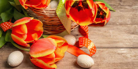 Easter card with eggs and bouquet of fresh tulips on vintage wooden background. The minimal concept...