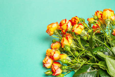 Bouquet of bright yellow-orange roses on turquoise background. Festive gift, greeting card for Easter, Birthday, Valentines Day or Wedding. Holiday concept, a place for text, top viewの写真素材