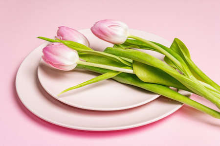 Festive creative pink table setting with tulips on gentle rosy background. Valentine's Day, Wedding, Birthday, Women's, and Mother's Day. Flat lay, copy spaceの写真素材