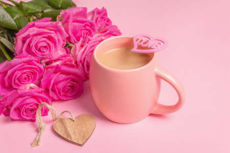 Morning coffee with a beautiful bouquet of roses. Romantic breakfast concept, wooden hearts, festive good mood. Pastel pink backgroundの写真素材