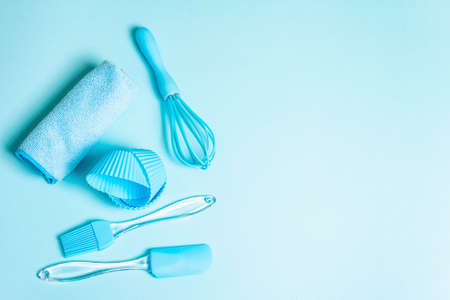 Baking concept isolated on pastel blue background. A set of spatula, whisk, brush, muffin tins and napkin. All objects are matched in the same color scheme, flat layの写真素材