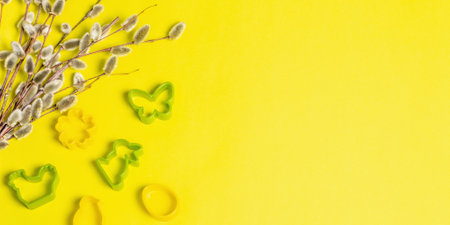 Easter baking concept isolated on sunny yellow background. A set of cookie cutters in the form of traditional festive Easter symbols. Bouquet of fresh willow sprigs, Bannerの写真素材
