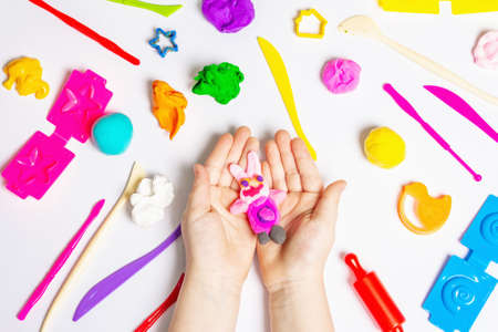 Children hands playing with colorful modeling clay on white background. Educational game with clay. Children sculpting figures from clay. Early development concept, top viewの写真素材