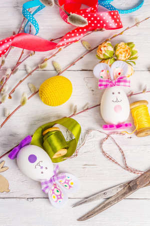 Festive Easter handmade concept. Traditional symbols with eggs, funny bunnies, accessories and materials for needlework. Children early development, white backgroundの写真素材