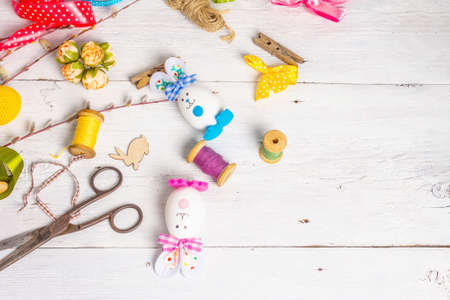 Festive Easter handmade concept. Traditional symbols with eggs, funny bunnies, accessories and materials for needlework. Children early development, white backgroundの写真素材