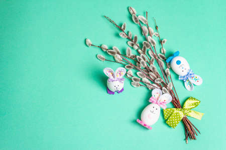 Sprig of willow isolated on pastel turquoise background. Willow seals, fluffy buds, handmade funny bunnies from the egg. Happy Easter conceptの写真素材