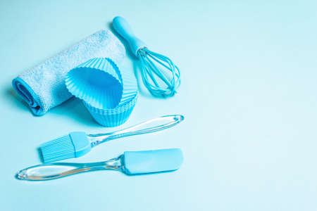 Baking concept isolated on pastel blue background. A set of spatula, whisk, brush, muffin tins and napkin. All objects are matched in the same color scheme, flat layの写真素材