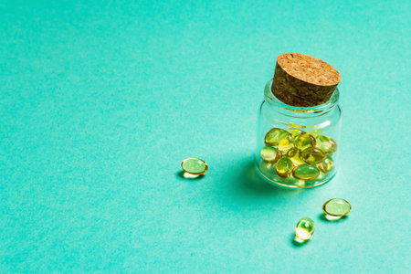 Omega-3 tablets in an old bottle on a turquoise matte background. Healthy life concept, prevention...