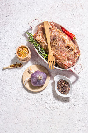 Raw pork roll stuffed with garlic and carrots in a ceramic roasting dish. Fresh meat, spices,...