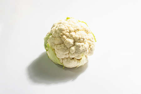 A fresh head of cauliflower isolated on white background. Raw single vegetable, healthy food concept, vegan or vegetarian lifestyle. Trendy hard light, dark shadow, flat lay, mockup, templateの写真素材