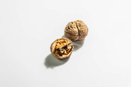 Whole and half walnuts isolated on white background. Healthy food concept, vegan or vegetarian lifestyle. A trendy hard light, dark shadow, flat lay, mockup, templateの写真素材