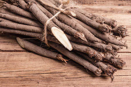 Bunch of raw Scorzonera or Spanish salsify. Very healthy modern vegetable, suitable for diabetics. Trendy ingredient for vegan or vegetarian food. Vintage wooden table, copy spaceの写真素材