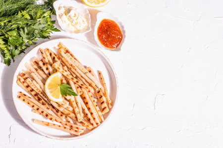Grilled scorzonera with sauces set. Modern hard light, dark shadow. Ceramic stand, spices, fashion napkin. White plaster background, top viewの写真素材