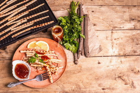 Grilled scorzonera with sauce. Cutlery, rustic ceramic plates, grill, spices. Old wooden boards...