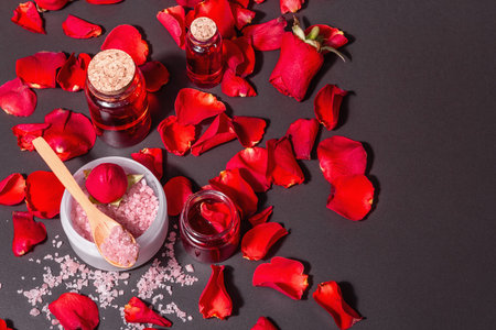 Natural spa concept with fresh roses petals. Rose sea salt, essential oil, soft towels. Modern hard...