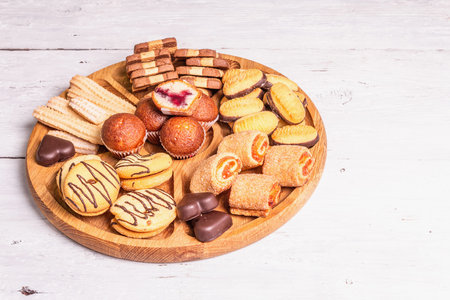 Assorted various cookies and muffins. Trendy hard light, dark shadow. Wooden combination plate on...