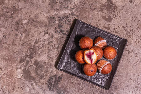Cupcakes stuffed currant jam. Modern hard light, dark shadow. Ceramic stand, stone concrete background, top viewの写真素材