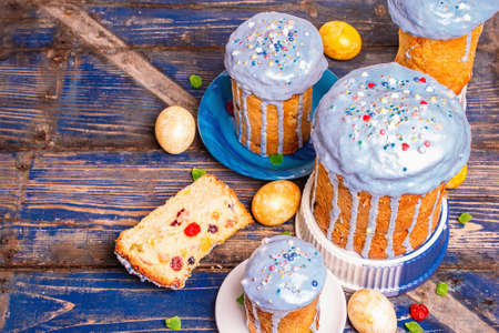 Easter cake with blue icing, topping, edible beads. Natural healthy ingredients, golden eggs, festive decor. Modern stands, vintage wooden table background, top viewの写真素材