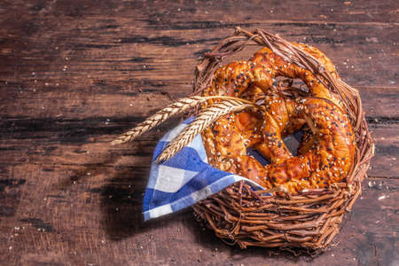 Oktoberfest concept - pretzels, spikelets, traditional napkin in a wicker basket. Trendy hard light, dark shadow. Vintage wooden boards background, place for textの写真素材