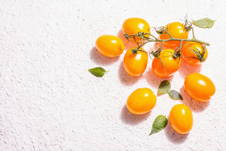 Yellow-orange tomatoes on light plaster background. Fresh ripe vegetables, harvesting concept. A...
