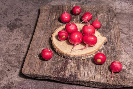 Pink ripe radish on a wooden stand. Fresh sweet vegetables, organic farmer product. Modern hard light, dark shadow, chopping board, marble stone background, copy spaceの写真素材