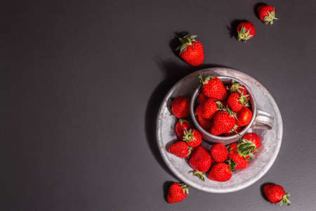 Concept of summer food with a strawberry on a black stone background. Ripe aromatic berries, modern hard light, dark shadow, top viewの写真素材