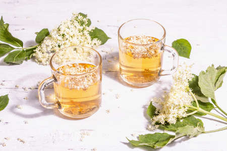 Elderberry flower tea. Refreshing summer drink, healthy lifestyle concept. Trendy hard light, dark shadow. Old white wooden boards background, close upの写真素材