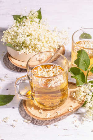 Elderberry flower tea. Refreshing summer drink, healthy lifestyle concept. Trendy hard light, dark shadow. Old white wooden boards background, close upの写真素材