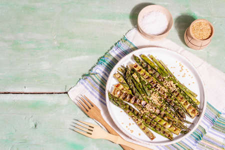 Ripe grilled asparagus. Golden flax seeds, sea salt, healthy and wholesome food concept. Modern hard light, dark shadow. Light green table, top viewの写真素材