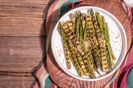 Ripe grilled asparagus. Rustic style arrangement, healthy food concept. Trendy hard light, dark shadow. Vintage wooden boards, top viewの写真素材