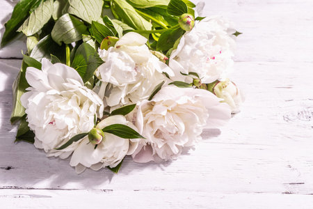 Bouquet of fresh white peonies. Summer delicate flowers, romantic gift concept. Floral arrangement, trendy hard light, dark shadows. White old planks background, top viewの写真素材