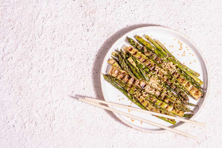 Ripe grilled asparagus. Golden flax seeds, healthy and wholesome food concept. Modern hard light, dark shadow. Light putty background, top viewの写真素材